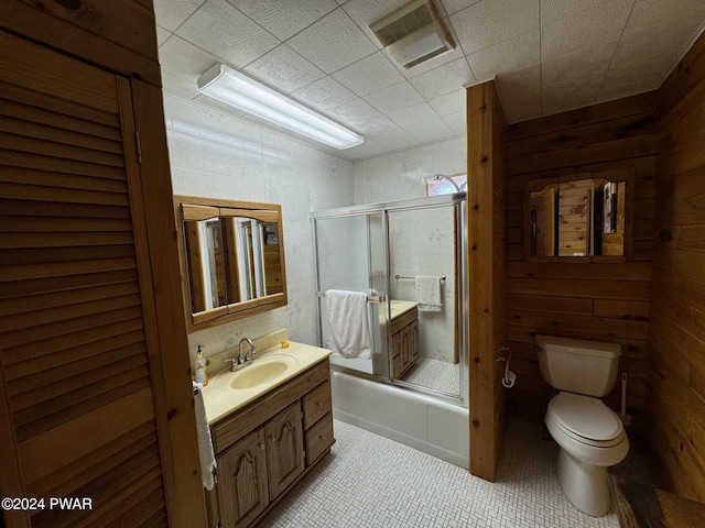 full bathroom featuring vanity, wood walls, toilet, and shower / bath combination with glass door