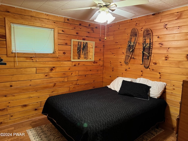 bedroom featuring ceiling fan and wood walls