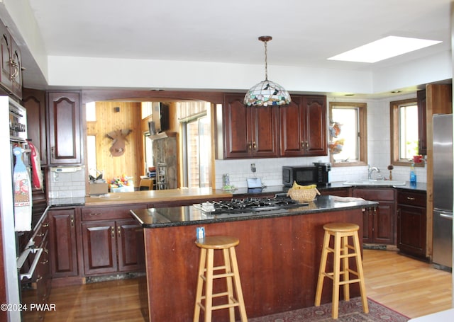 kitchen with a skylight, sink, a kitchen breakfast bar, a kitchen island, and black appliances