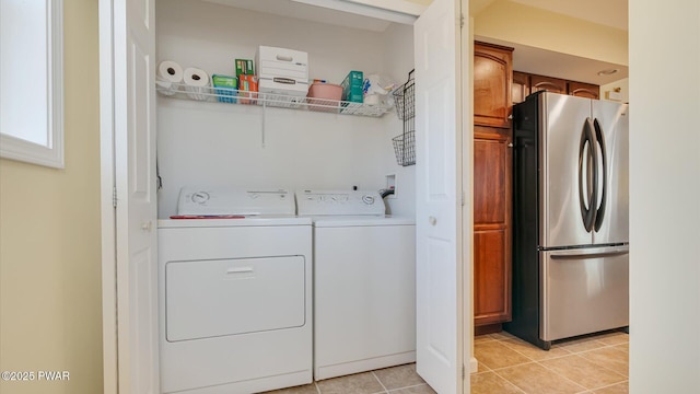 clothes washing area featuring light tile patterned floors, laundry area, and washer and clothes dryer