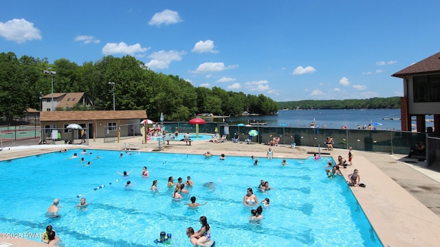 community pool featuring a water view, fence, and a patio area