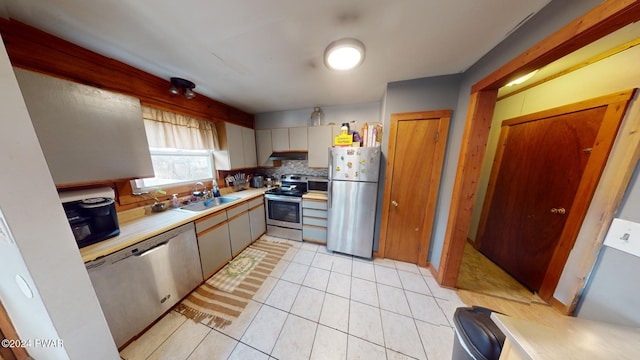 kitchen featuring light tile patterned floors, stainless steel appliances, tasteful backsplash, and sink