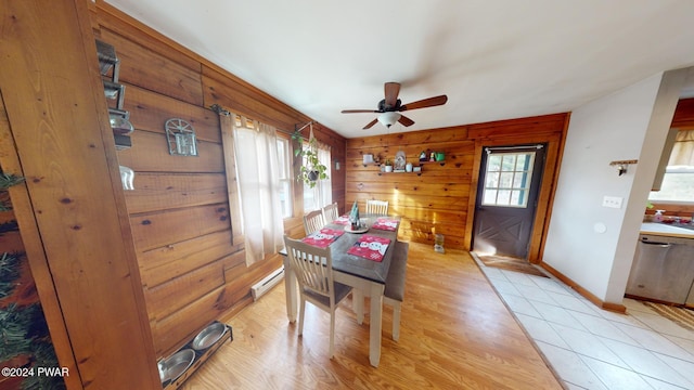 dining space with baseboard heating, plenty of natural light, wood walls, and ceiling fan