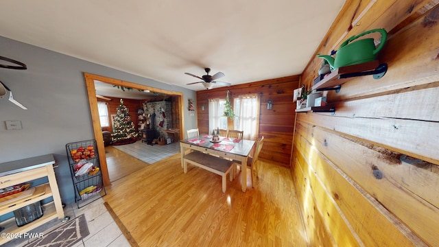 dining area with ceiling fan, wood walls, and light tile patterned floors