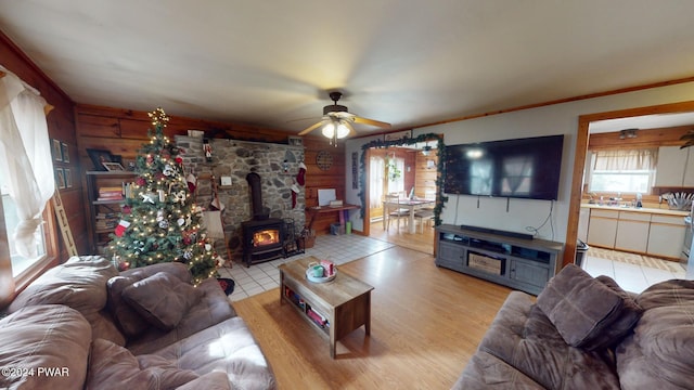 living room featuring ceiling fan, a wood stove, and ornamental molding