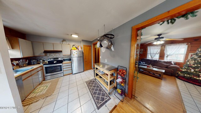 kitchen featuring backsplash, sink, light hardwood / wood-style flooring, ceiling fan, and stainless steel appliances