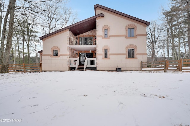 exterior space featuring fence, a balcony, and stucco siding