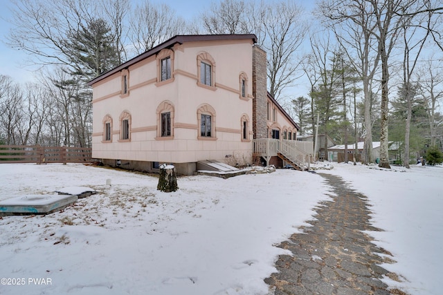 exterior space featuring fence, a chimney, and stucco siding