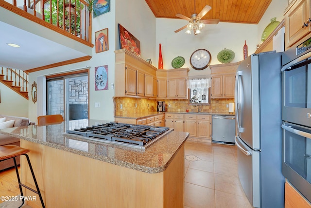 kitchen featuring appliances with stainless steel finishes, light brown cabinets, a kitchen breakfast bar, and light stone countertops