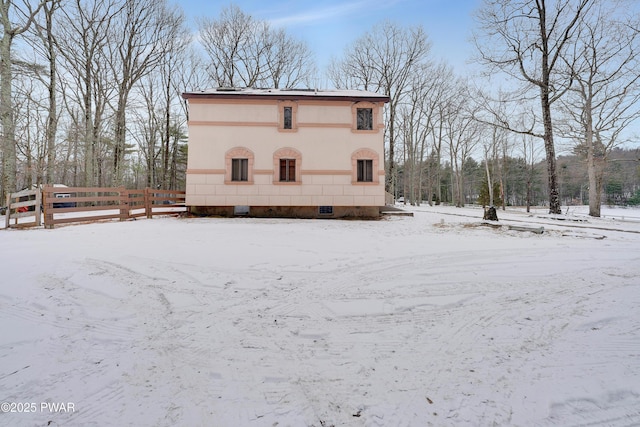 snow covered house featuring fence