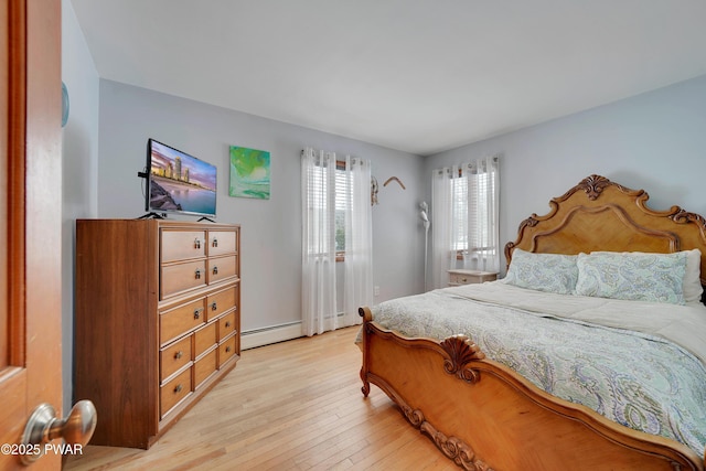 bedroom with light wood-style floors and a baseboard heating unit