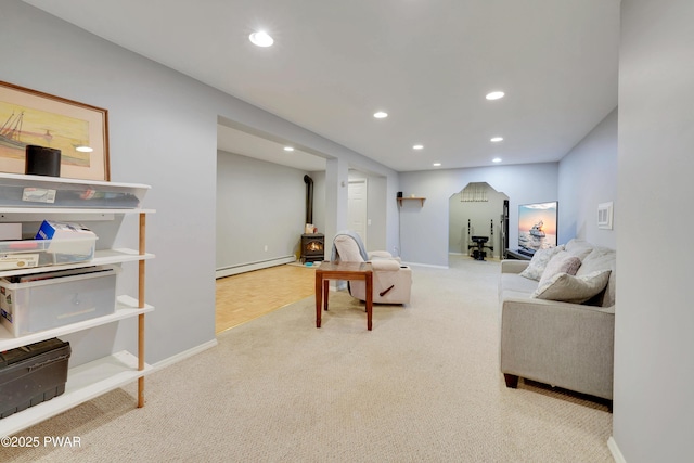 living area with a wood stove, a baseboard radiator, recessed lighting, and light colored carpet