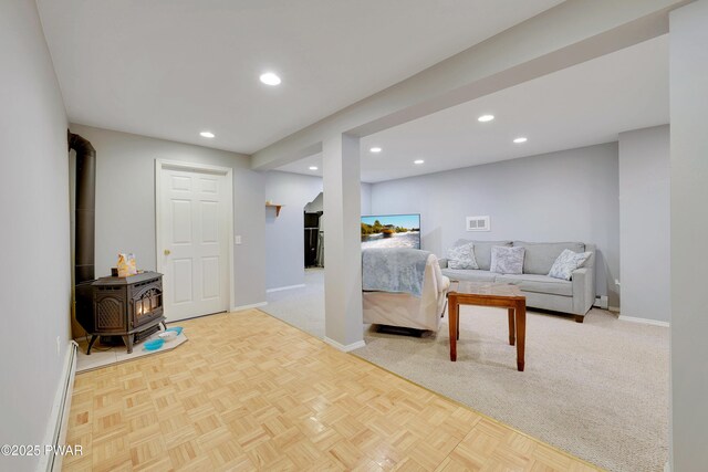 bedroom with a wood stove, baseboards, a baseboard heating unit, and recessed lighting