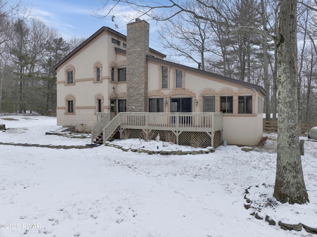 exterior space with a chimney, a wooden deck, and stucco siding