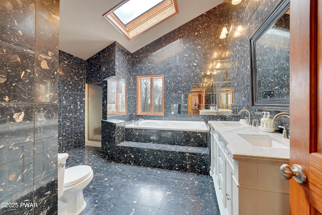 full bath featuring vaulted ceiling with skylight, a sink, tile walls, a bath, and double vanity