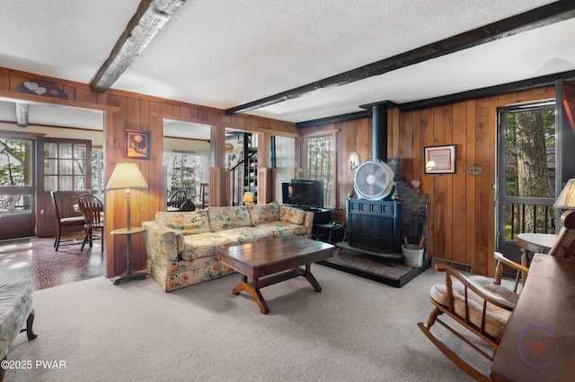 71 Boulder Point Rd, Lakeville, PA 18438 - carpeted living room featuring beam ceiling, a textured ceiling, a wood stove, healthy amount of natural light, and wooden walls