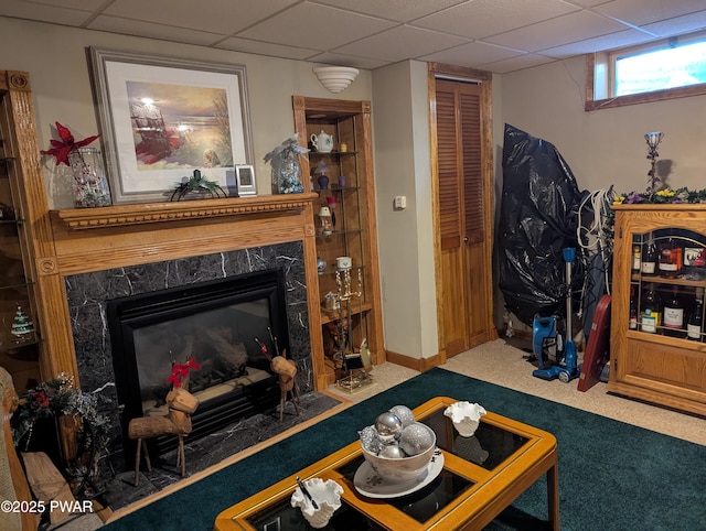 carpeted living area featuring a drop ceiling and a premium fireplace