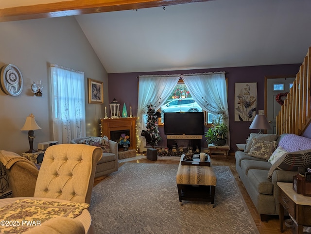 living room featuring a fireplace with raised hearth, stairs, and vaulted ceiling