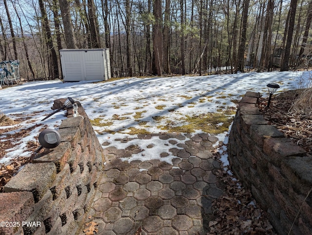 snowy yard featuring an outdoor structure and a storage unit