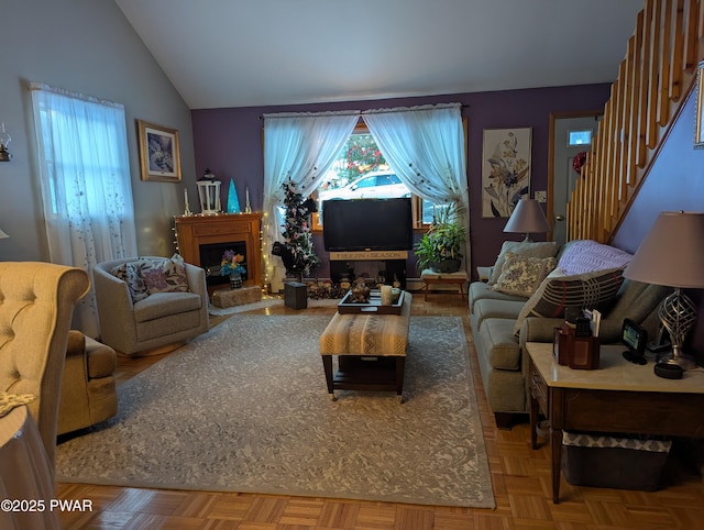 living room with lofted ceiling, stairway, a fireplace with raised hearth, and a wealth of natural light