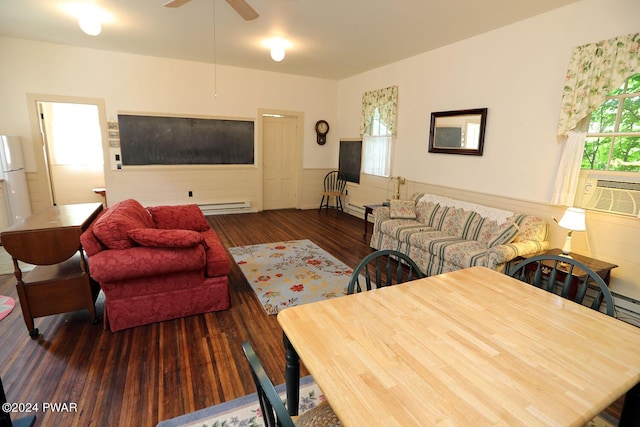 living room with cooling unit, baseboard heating, ceiling fan, and dark wood-type flooring