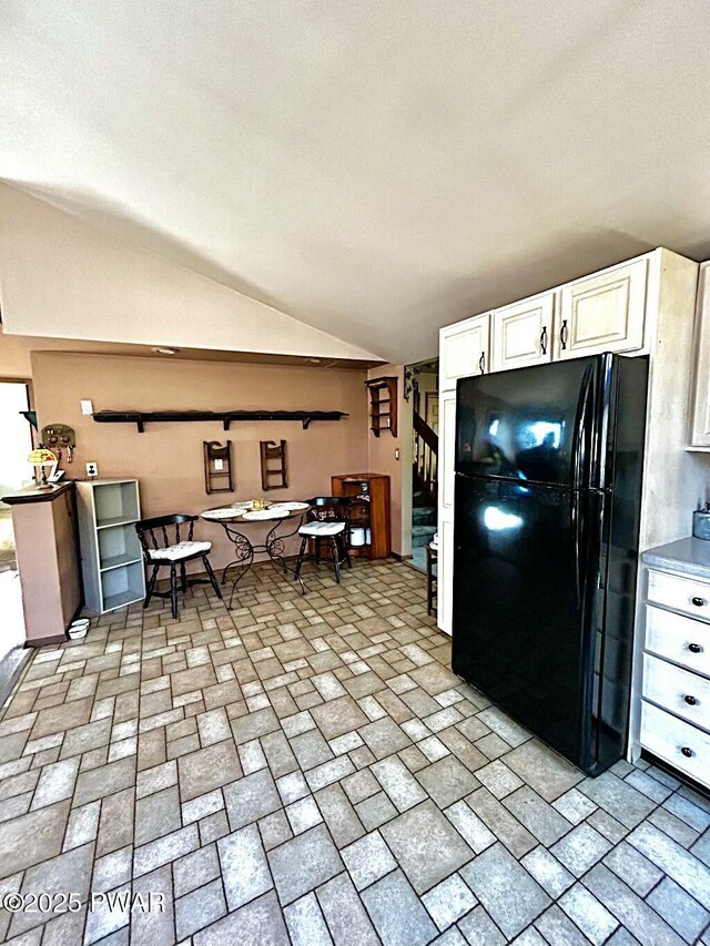 kitchen with white cabinets, vaulted ceiling with skylight, sink, and black appliances