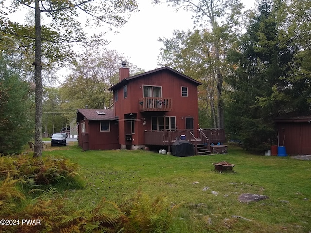 back of house featuring a balcony, a yard, a deck, and a fire pit