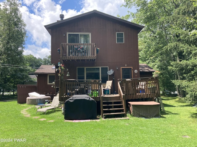 rear view of house with a lawn, a balcony, and a deck