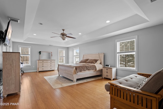 bedroom with recessed lighting, visible vents, baseboards, light wood-style floors, and a tray ceiling