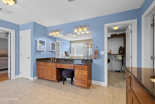 ensuite bathroom with visible vents, connected bathroom, vanity, a shower stall, and tile patterned flooring