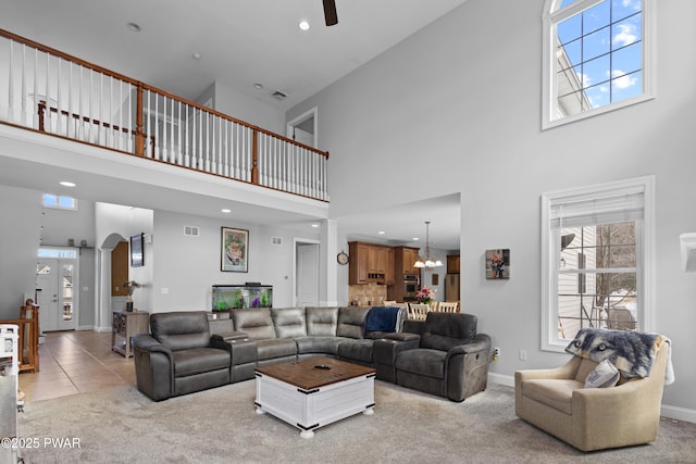 living area with arched walkways, baseboards, visible vents, and carpet