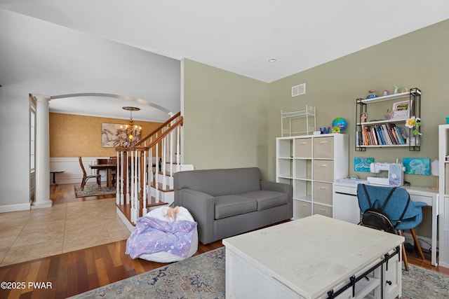 living area with arched walkways, decorative columns, a notable chandelier, light wood finished floors, and visible vents