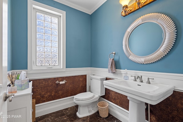 half bathroom featuring ornamental molding, wainscoting, and toilet