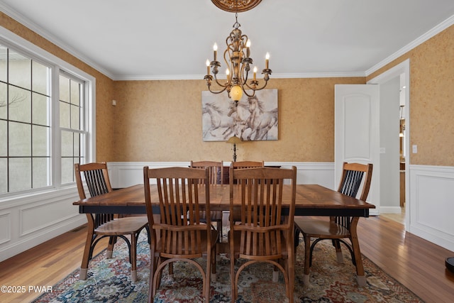 dining room featuring a wainscoted wall, wood finished floors, and crown molding