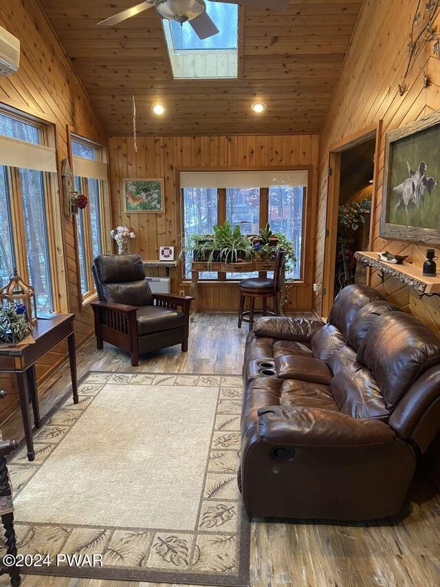 living room featuring wooden ceiling, vaulted ceiling with skylight, ceiling fan, a wall mounted AC, and wood-type flooring