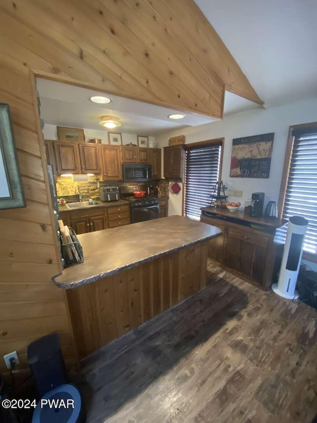 kitchen featuring kitchen peninsula, vaulted ceiling, sink, black appliances, and dark hardwood / wood-style floors