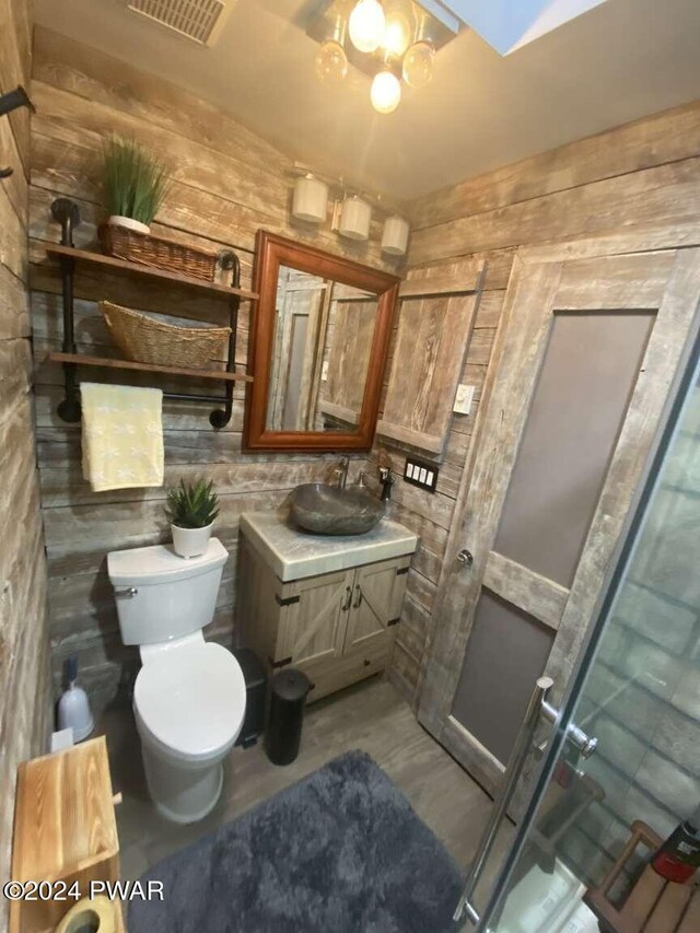 bathroom with vanity, toilet, and wooden walls