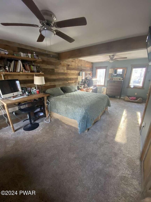 carpeted bedroom featuring ceiling fan and wooden walls