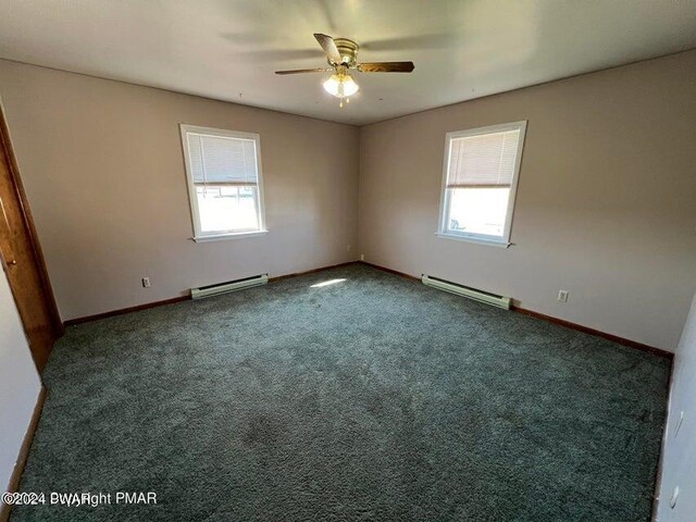 spare room with plenty of natural light, a baseboard radiator, and dark colored carpet