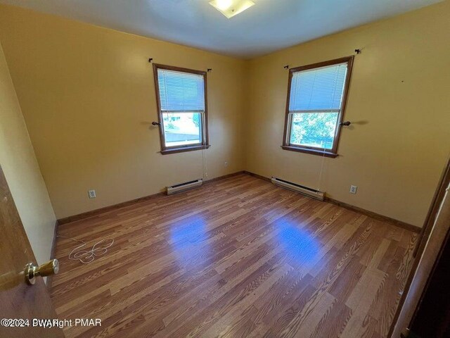 empty room with a baseboard radiator and hardwood / wood-style flooring