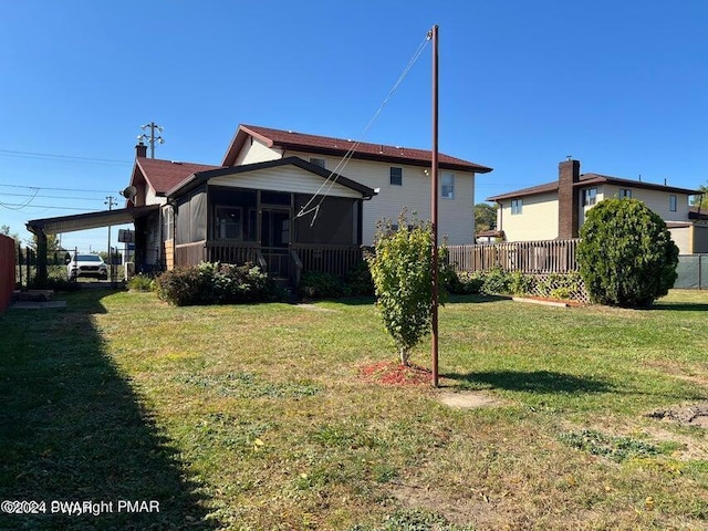 back of property with a sunroom and a lawn