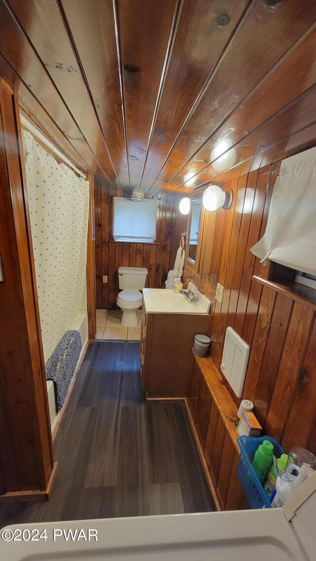 bathroom featuring vanity, wooden walls, a shower with shower curtain, toilet, and wood ceiling