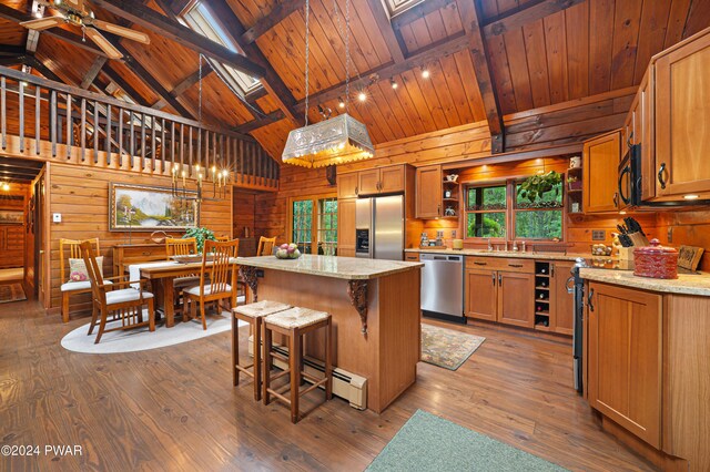 kitchen featuring a skylight, stainless steel appliances, pendant lighting, beam ceiling, and a center island