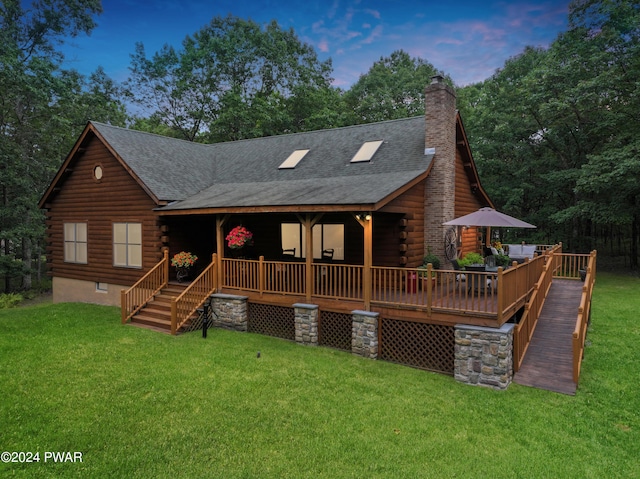 back house at dusk with a wooden deck and a lawn