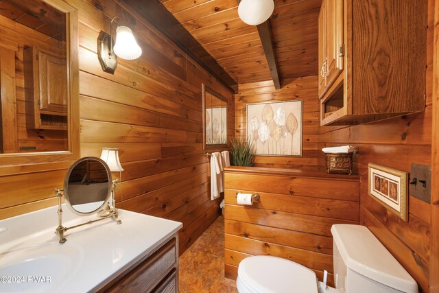 bathroom featuring beamed ceiling, wood walls, toilet, vanity, and wood ceiling