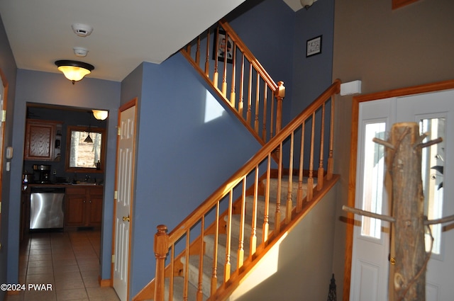 stairs featuring tile patterned flooring, plenty of natural light, and sink