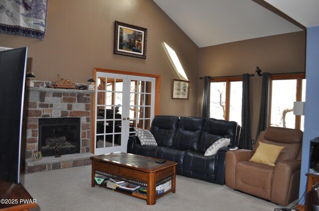 living room featuring carpet, a stone fireplace, lofted ceiling, and french doors