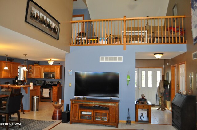 living room with a fireplace, light tile patterned floors, and a high ceiling