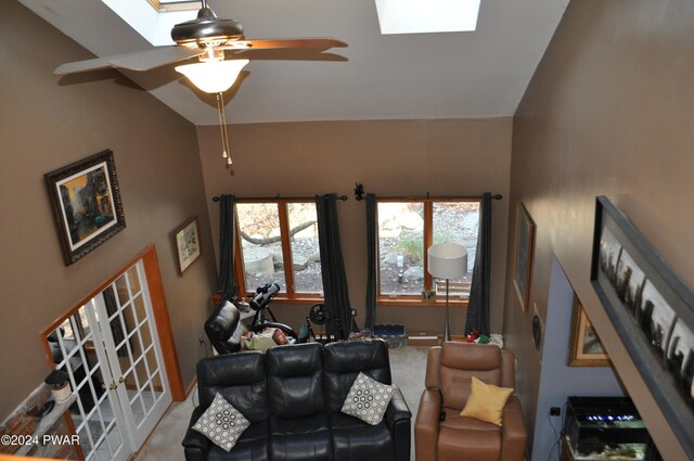 carpeted living room featuring french doors, ceiling fan, and vaulted ceiling with skylight