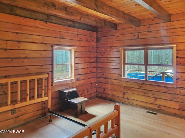 bedroom with beamed ceiling, wood walls, light wood-type flooring, and wooden ceiling